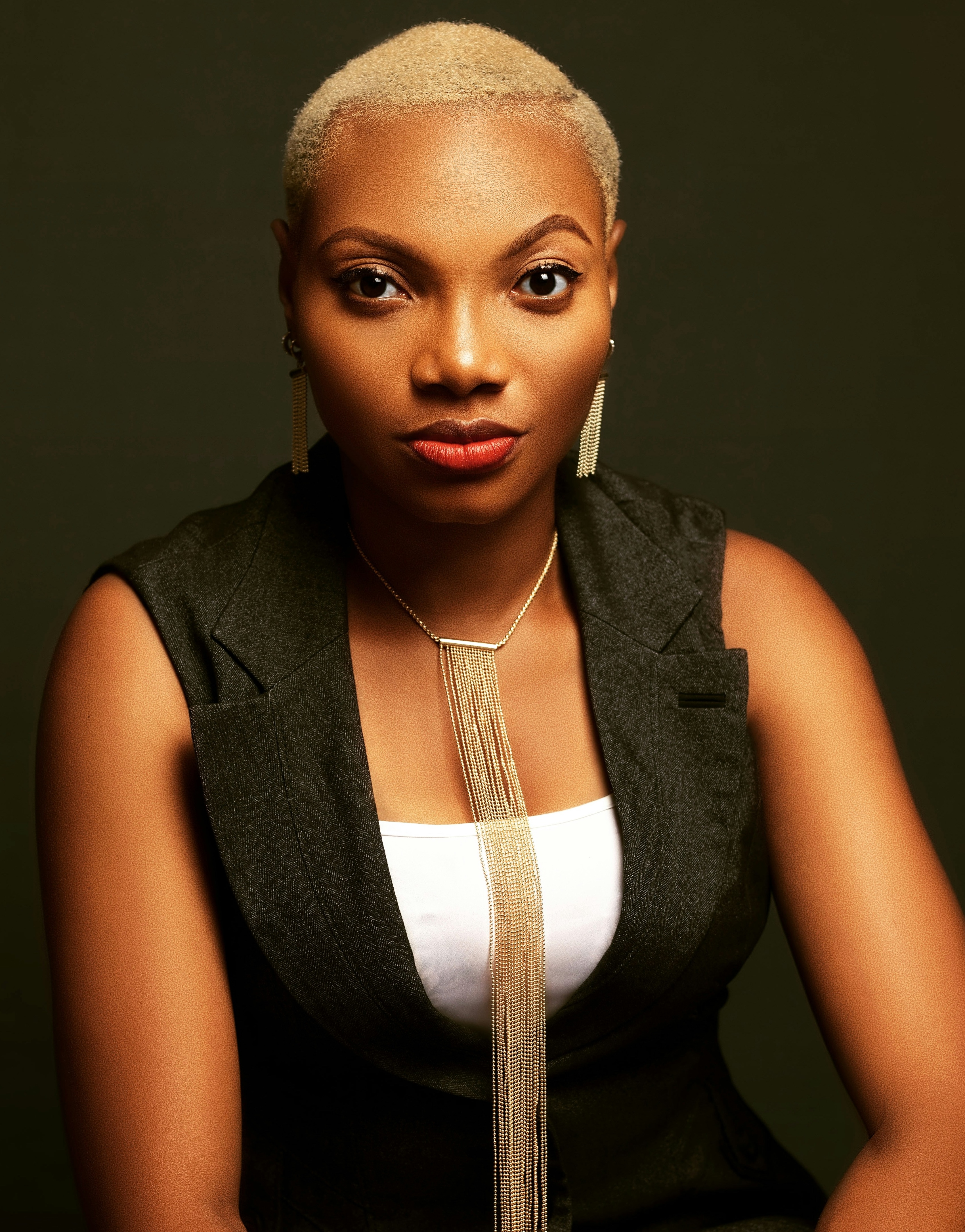 photo of colorist Alita N. with short-cropped gold hair and a long gold necklace